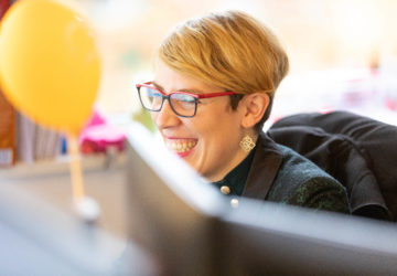 Collaboratrice MV Group souriant, face à son ordinateur, ballon gonflable jaune derrière elle