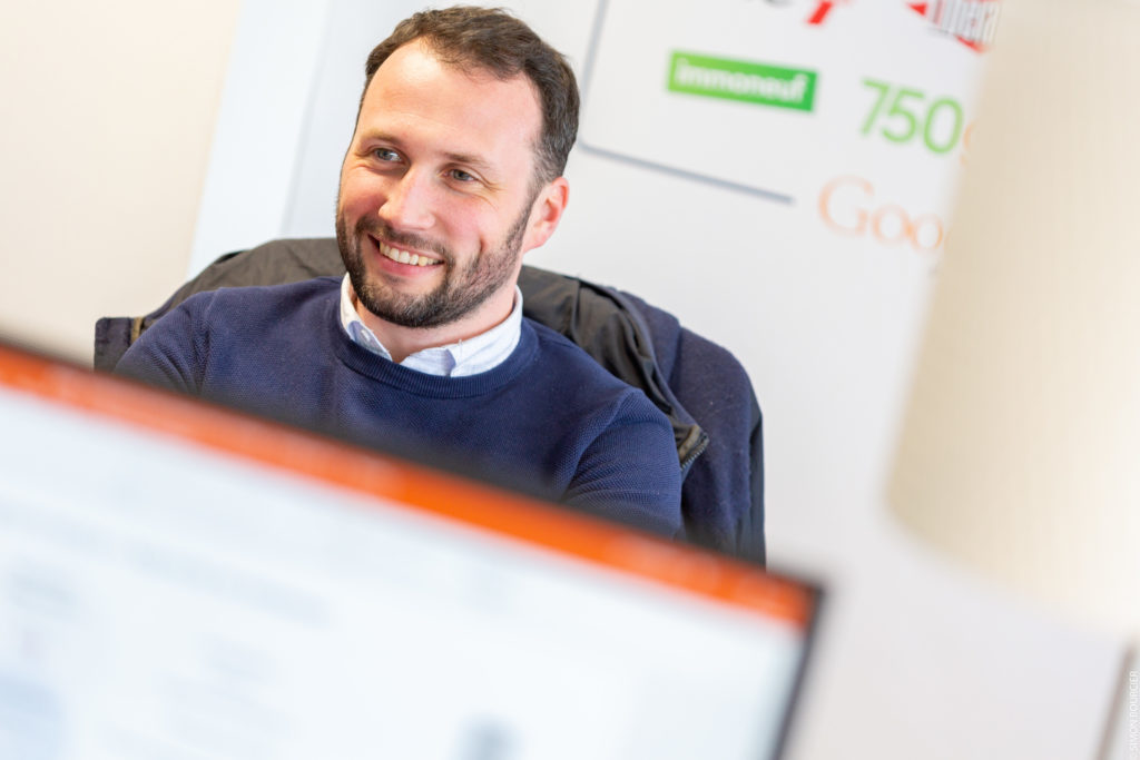 Collaborateur MV Group souriant, un écran flou au premier plan